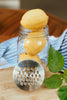 Glass jar with lemons and a metal grater on a wooden surface